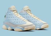 Air Jordan 13 Retro SoleFly DX5763-100 en suède et ripstop blanc, gris et bleu ciel avec hologramme cat’s eye et semelle gum vue de 3/4 face. 