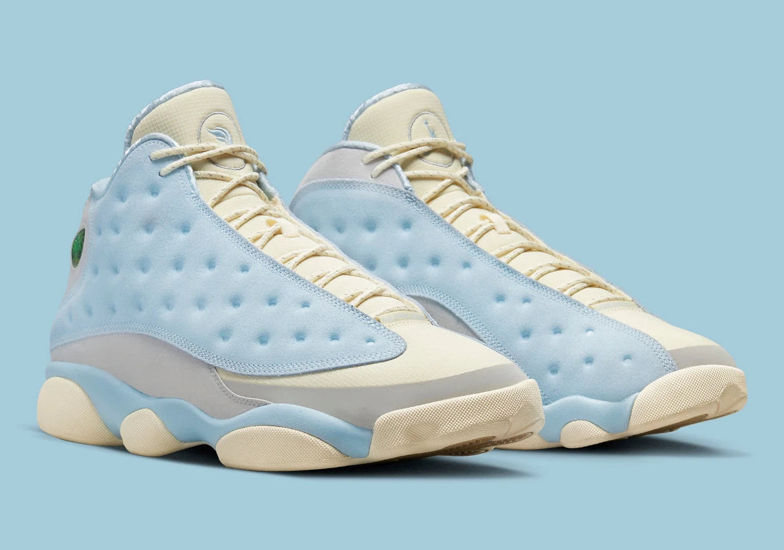 Air Jordan 13 Retro SoleFly DX5763-100 en suède et ripstop blanc, gris et bleu ciel avec hologramme cat’s eye et semelle gum vue de 3/4 face. 