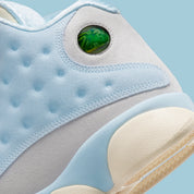 Vue zoomée sur l'arrière de la Air Jordan 13 Retro SoleFly DX5763-100 en suède et ripstop blanc, gris et bleu ciel avec hologramme cat’s eye et semelle gum.