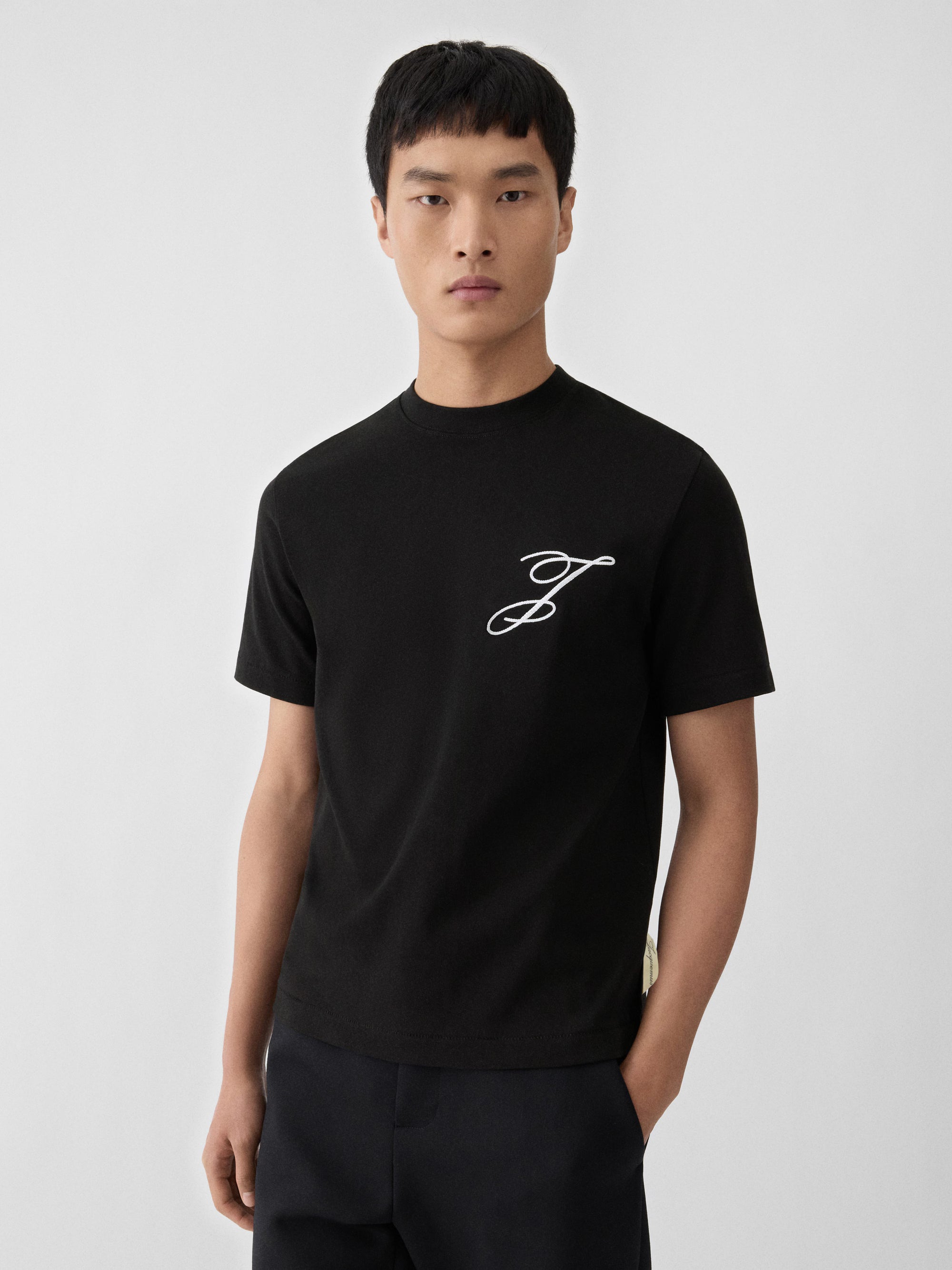 T-shirt Jacquemus en coton noir premium avec logo script blanc, au design minimaliste et élégant.
