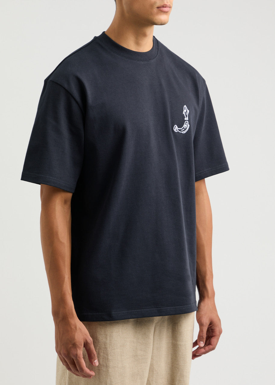 TEE SHIRT JACQUEMUS BLEU MARINE AVEC UN LOGO "J" EN FORME DE POISSON SUR LE COEUR ET UN GROS CADRE INSCRIT JACQUEMUS AU DOS DU TEE-SHIRT