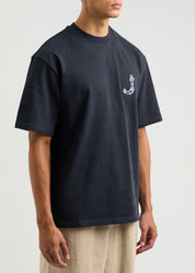 TEE SHIRT JACQUEMUS BLEU MARINE AVEC UN LOGO "J" EN FORME DE POISSON SUR LE COEUR ET UN GROS CADRE INSCRIT JACQUEMUS AU DOS DU TEE-SHIRT