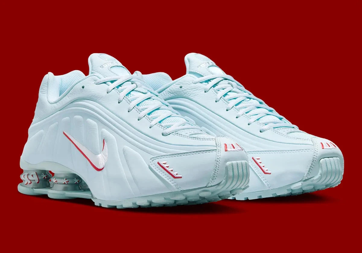 Nike Shox R4 Puerto Rico avec tige Glacier Blue en cuir synthétique, détails University Red et Metallic Silver, graphismes PR, porte-bonheur Vejigante et amorti Nike Shox à quatre colonnes.