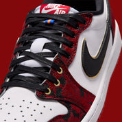 Vue zoomée sur les détails latéraux de la Air Jordan 1 Retro Low OG Last Dance At The Garden IR0088-001 en cuir blanc avec empiècements floraux rouges et noirs, Swoosh noir bordé d’or et accents Knicks.