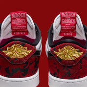 Air Jordan 1 Retro Low OG Last Dance At The Garden IR0088-001 en cuir blanc avec empiècements floraux rouges et noirs, Swoosh noir bordé d’or et accents Knicks vue détaillée de la languette. 