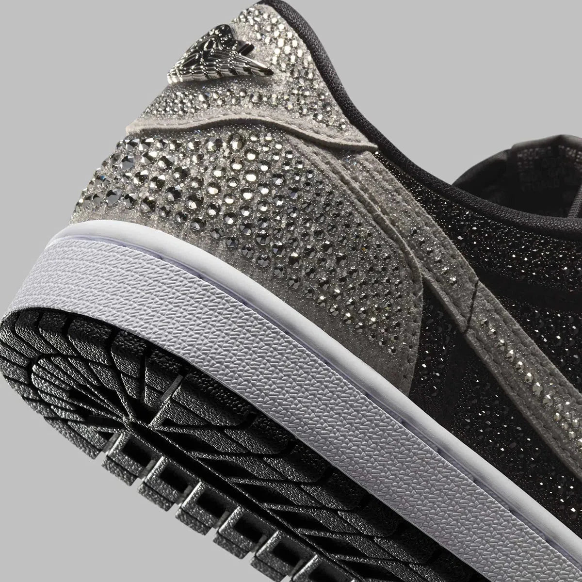 Image de la Jordan 1 Retro Low OG Swarovski Stealth pour femme, sneaker en cuir gris avec Swoosh incrusté de cristaux Swarovski et semelle Air encapsulée. Vue zoomée sur les détails de l'arrière de la paire. 