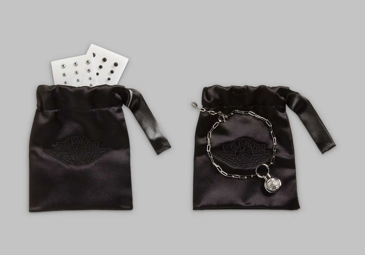 Image de la Jordan 1 Retro Low OG Swarovski Stealth pour femme, sneaker en cuir gris avec Swoosh incrusté de cristaux Swarovski et semelle Air encapsulée. Vue sur les sacs disponibles dans la boite. 