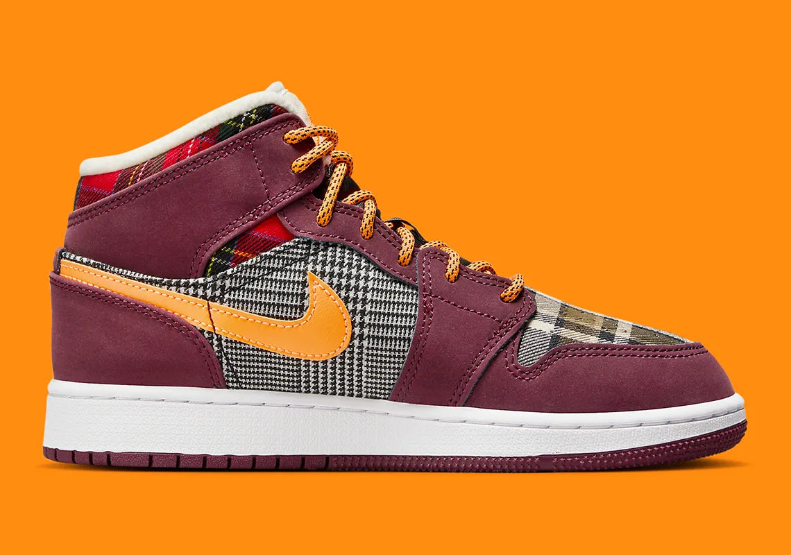 Air Jordan 1 Mid SE Plaid, sneaker mi-montante bordeaux, noire et blanche avec panneaux à carreaux tartan et détails orange.