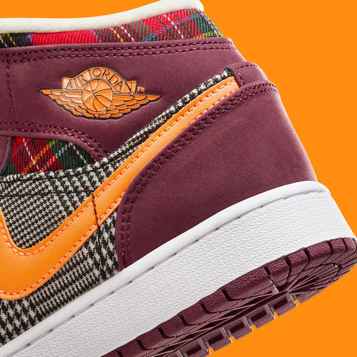 Air Jordan 1 Mid SE Plaid, sneaker mi-montante bordeaux, noire et blanche avec panneaux à carreaux tartan et détails orange.