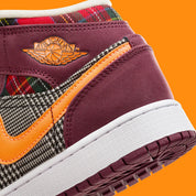 Air Jordan 1 Mid SE Plaid, sneaker mi-montante bordeaux, noire et blanche avec panneaux à carreaux tartan et détails orange.