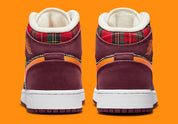 Air Jordan 1 Mid SE Plaid, sneaker mi-montante bordeaux, noire et blanche avec panneaux à carreaux tartan et détails orange.