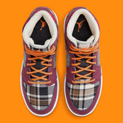 Air Jordan 1 Mid SE Plaid, sneaker mi-montante bordeaux, noire et blanche avec panneaux à carreaux tartan et détails orange.
