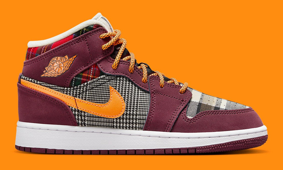 Air Jordan 1 Mid SE Plaid, sneaker mi-montante bordeaux, noire et blanche avec panneaux à carreaux tartan et détails orange.