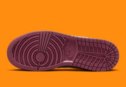 Air Jordan 1 Mid SE Plaid, sneaker mi-montante bordeaux, noire et blanche avec panneaux à carreaux tartan et détails orange.