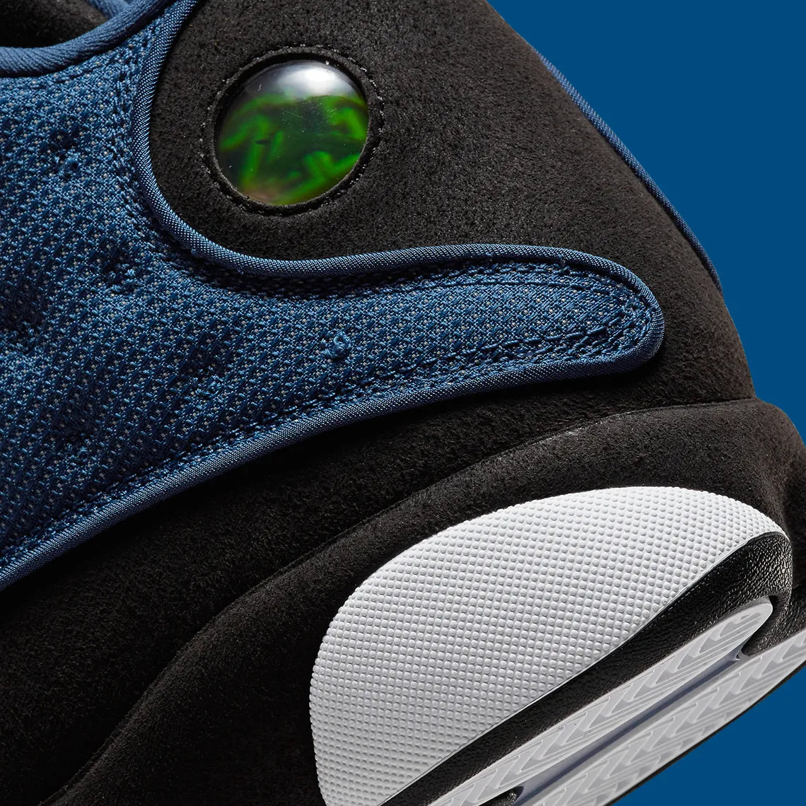 Vue zoomée sur les détails arrières de la Air Jordan 13 Retro Brave Blue DJ5982-400 en bleu marine et noir avec détails blancs, Jumpman University Blue et hologramme latéral.