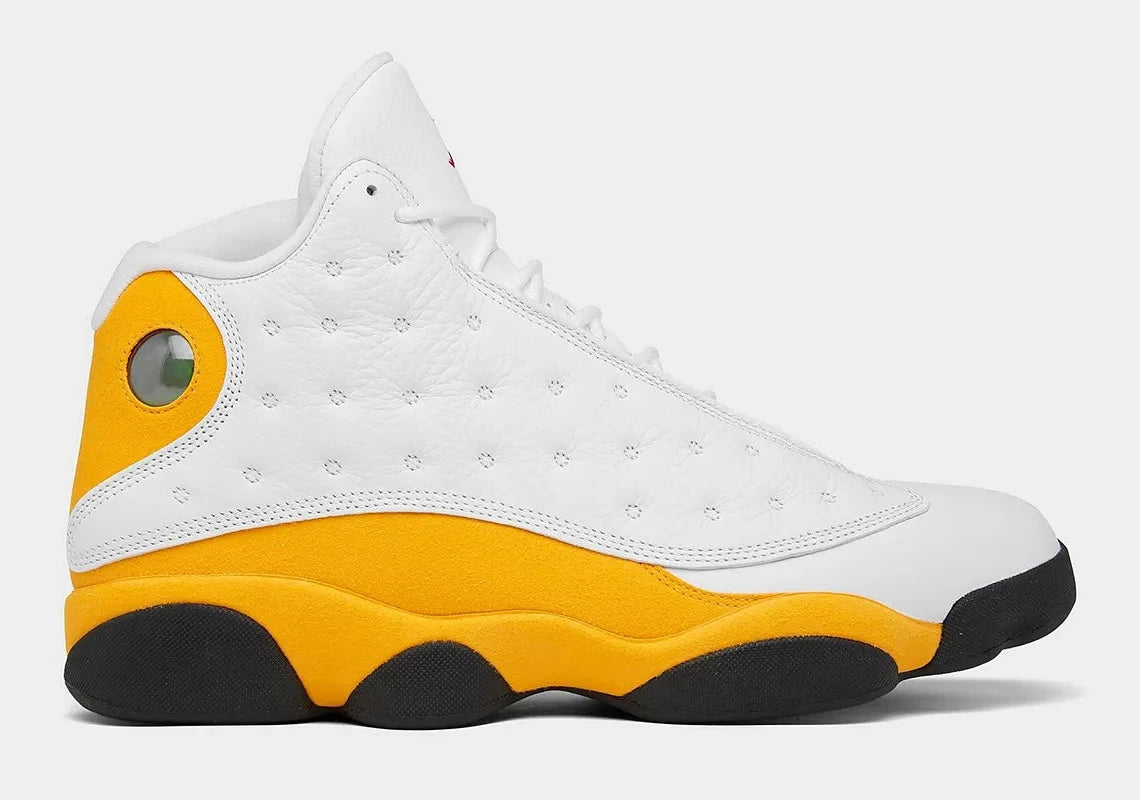 Air Jordan 13 Retro Del Sol 414571-167 en cuir blanc avec accents jaunes Del Sol, détails rouges, noirs et hologramme latéral vert vue de profil. 