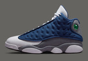Air Jordan 13 Retro Flint 2026, sneaker Jordan Brand en cuir blanc, mesh réfléchissant bleu marine et suède Flint Grey avec amorti Zoom Air et œil holographique.