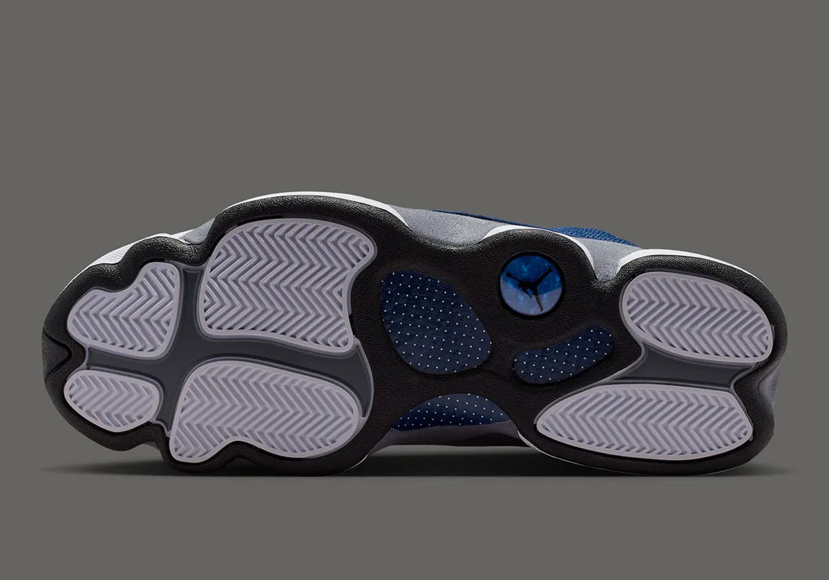 Air Jordan 13 Retro Flint 2026, sneaker Jordan Brand en cuir blanc, mesh réfléchissant bleu marine et suède Flint Grey avec amorti Zoom Air et œil holographique.