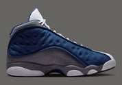 Air Jordan 13 Retro Flint 2026, sneaker Jordan Brand en cuir blanc, mesh réfléchissant bleu marine et suède Flint Grey avec amorti Zoom Air et œil holographique.