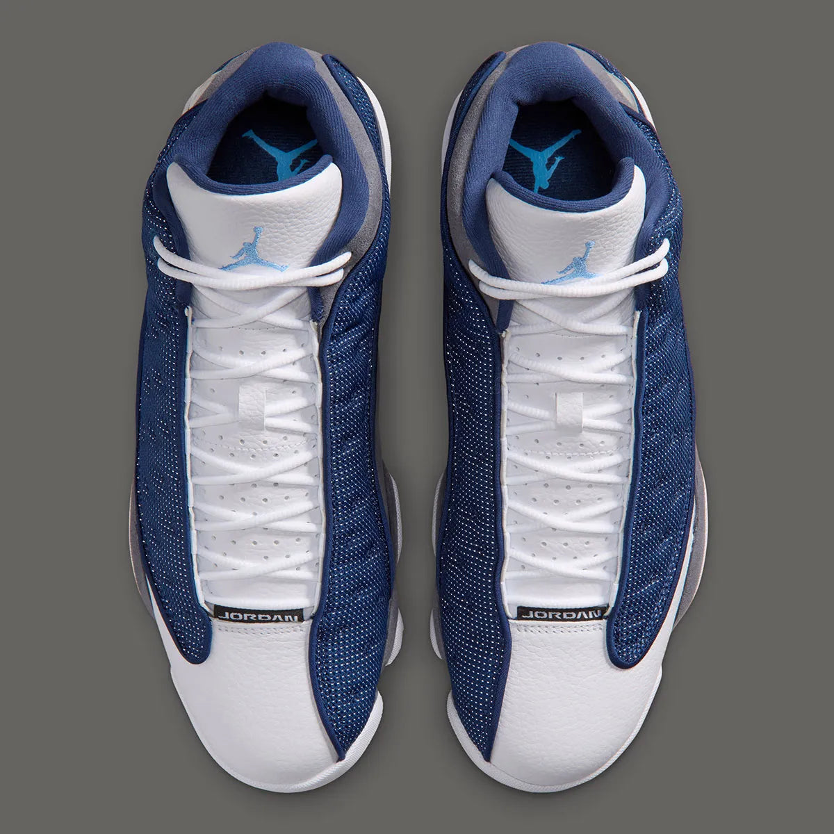 Air Jordan 13 Retro Flint 2026, sneaker Jordan Brand en cuir blanc, mesh réfléchissant bleu marine et suède Flint Grey avec amorti Zoom Air et œil holographique.