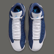 Air Jordan 13 Retro Flint 2026, sneaker Jordan Brand en cuir blanc, mesh réfléchissant bleu marine et suède Flint Grey avec amorti Zoom Air et œil holographique.