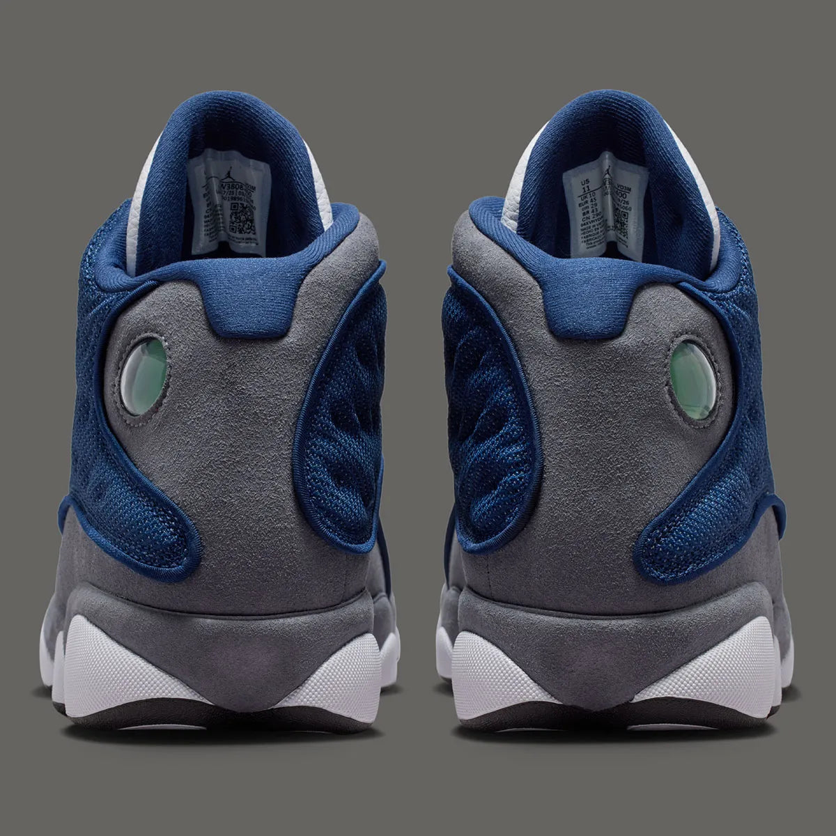 Air Jordan 13 Retro Flint 2026, sneaker Jordan Brand en cuir blanc, mesh réfléchissant bleu marine et suède Flint Grey avec amorti Zoom Air et œil holographique.