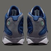 Air Jordan 13 Retro Flint 2026, sneaker Jordan Brand en cuir blanc, mesh réfléchissant bleu marine et suède Flint Grey avec amorti Zoom Air et œil holographique.