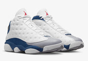 Air Jordan 13 Retro French Blue 414571-164 en cuir blanc avec panneaux French Blue, avant-pied gris, Jumpman rouge et hologramme latéral vue de 3/4 face. 