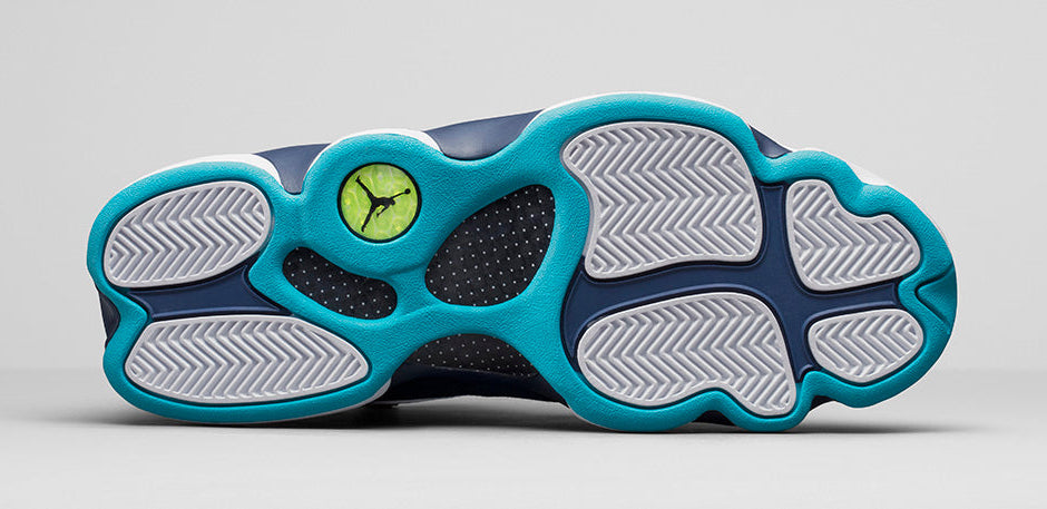 Air Jordan 13 Retro Low Hornets 310810-107 en cuir blanc avec empiècements Midnight Navy, accents Turquoise Blue et Jumpman métallique vue de dessous. 