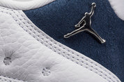Vue zoomée sur le jumpman de la Air Jordan 13 Retro Low Hornets 310810-107 en cuir blanc avec empiècements Midnight Navy, accents Turquoise Blue et Jumpman métallique.