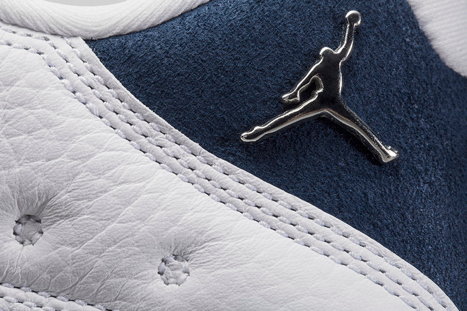 Vue zoomée sur le jumpman de la Air Jordan 13 Retro Low Hornets 310810-107 en cuir blanc avec empiècements Midnight Navy, accents Turquoise Blue et Jumpman métallique.