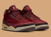 Air Jordan 3 Retro PRM Bin23 en cuir premium brun avec sceau rouge Bin23 et amorti Air visible emblématique.
