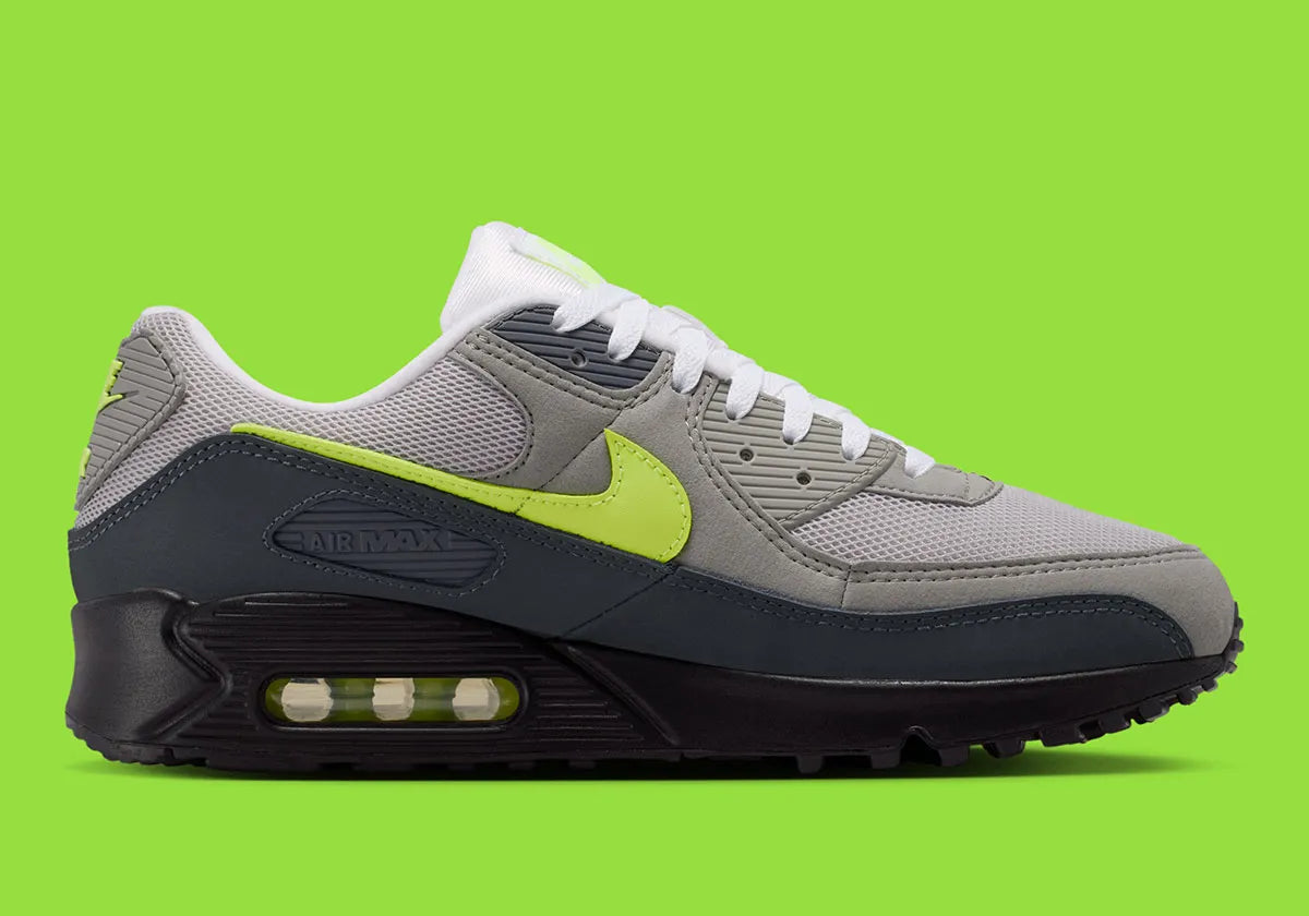 Nike Air Max 90 Neon, sneaker grise et noire avec Swoosh vert Neon, empiècements en mesh et unité Max Air visible au talon.