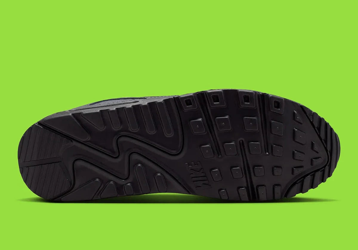 Nike Air Max 90 Neon, sneaker grise et noire avec Swoosh vert Neon, empiècements en mesh et unité Max Air visible au talon.
