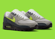 Nike Air Max 90 Neon, sneaker grise et noire avec Swoosh vert Neon, empiècements en mesh et unité Max Air visible au talon.