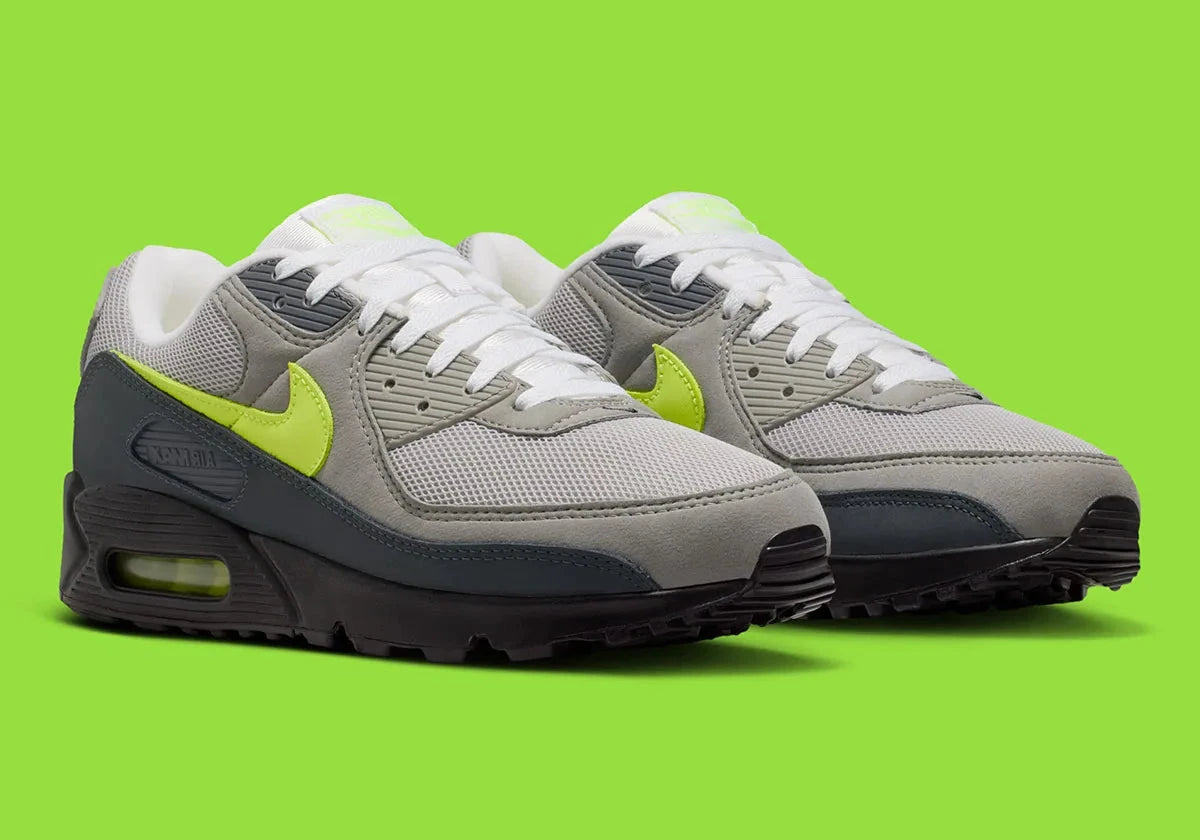 Nike Air Max 90 Neon, sneaker grise et noire avec Swoosh vert Neon, empiècements en mesh et unité Max Air visible au talon.