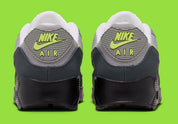 Nike Air Max 90 Neon, sneaker grise et noire avec Swoosh vert Neon, empiècements en mesh et unité Max Air visible au talon.