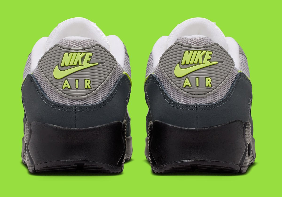 Nike Air Max 90 Neon, sneaker grise et noire avec Swoosh vert Neon, empiècements en mesh et unité Max Air visible au talon.