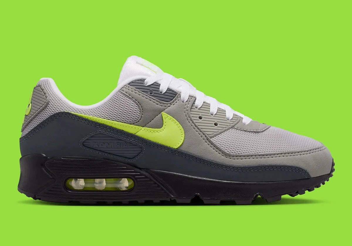 Nike Air Max 90 Neon, sneaker grise et noire avec Swoosh vert Neon, empiècements en mesh et unité Max Air visible au talon.