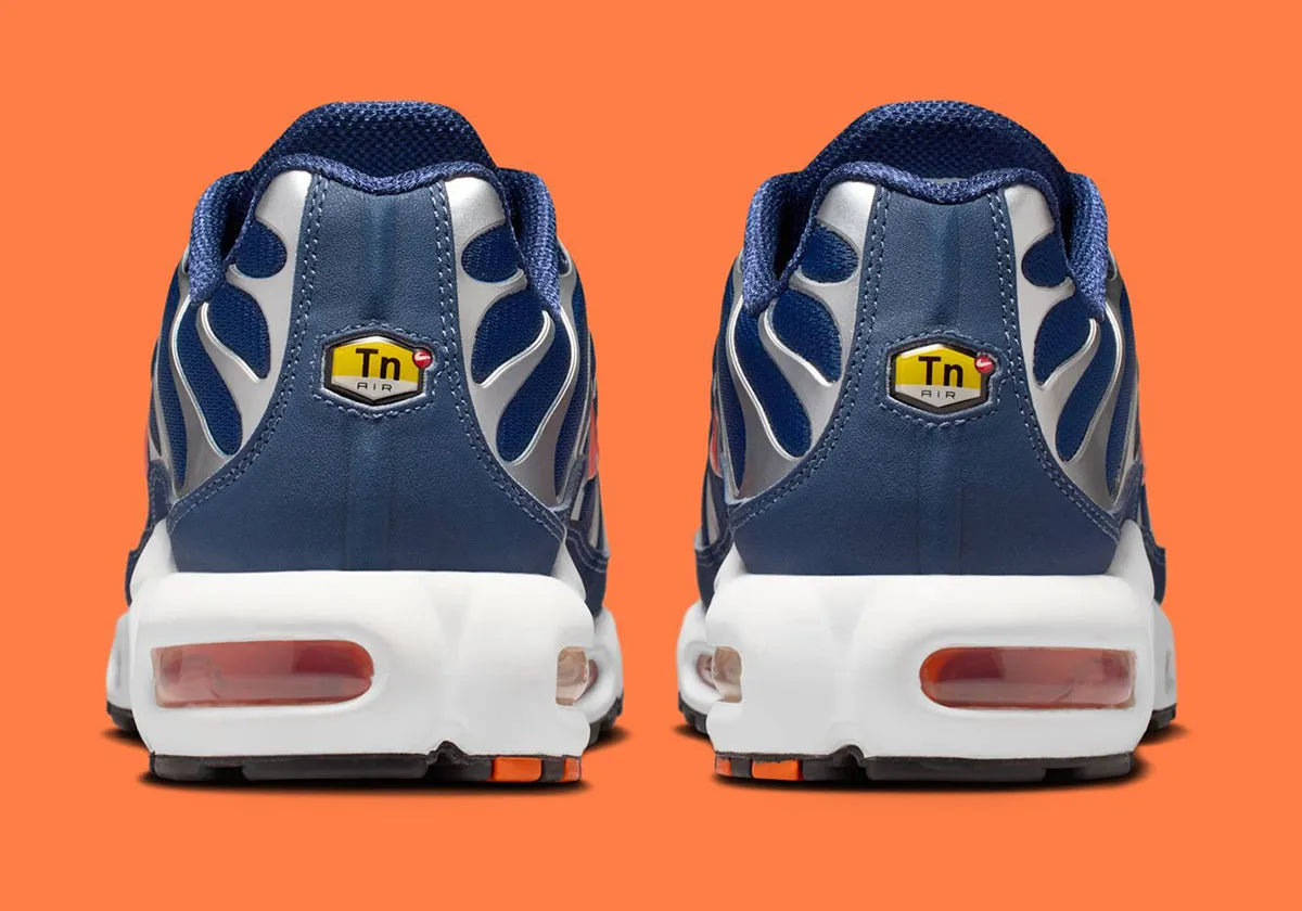 Nike Air Max Plus Syracuse bleu marine avec cage TPU gris argenté, Swoosh orange et unités Tuned Air visibles vue de derrière. 