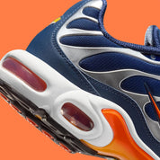 Vue zoomée sur les détails arrières de la Nike Air Max Plus Syracuse bleu marine avec cage TPU gris argenté, Swoosh orange et unités Tuned Air visibles.