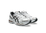 ASICS GEL-KAYANO 12.1 blanche, gris graphite et brune, avec tige en mesh respirant, empiècements synthétiques, amorti GEL et semelle extérieure en caoutchouc.