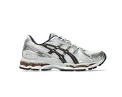 ASICS GEL-KAYANO 12.1 blanche, gris graphite et brune, avec tige en mesh respirant, empiècements synthétiques, amorti GEL et semelle extérieure en caoutchouc.