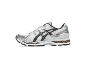 ASICS GEL-KAYANO 12.1 blanche, gris graphite et brune, avec tige en mesh respirant, empiècements synthétiques, amorti GEL et semelle extérieure en caoutchouc.

