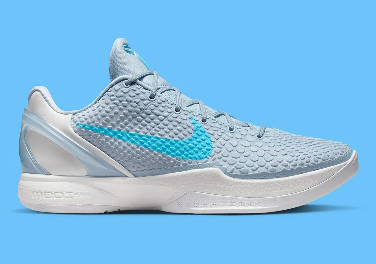 Image de la Nike Kobe 6 Protro “Caitlin Clark Light Armory Blue”, sneaker bleu glacier avec texture snakeskin, accents bleu baltic, semelle blanche, unité Zoom Air avant-pied. Vue de profil.