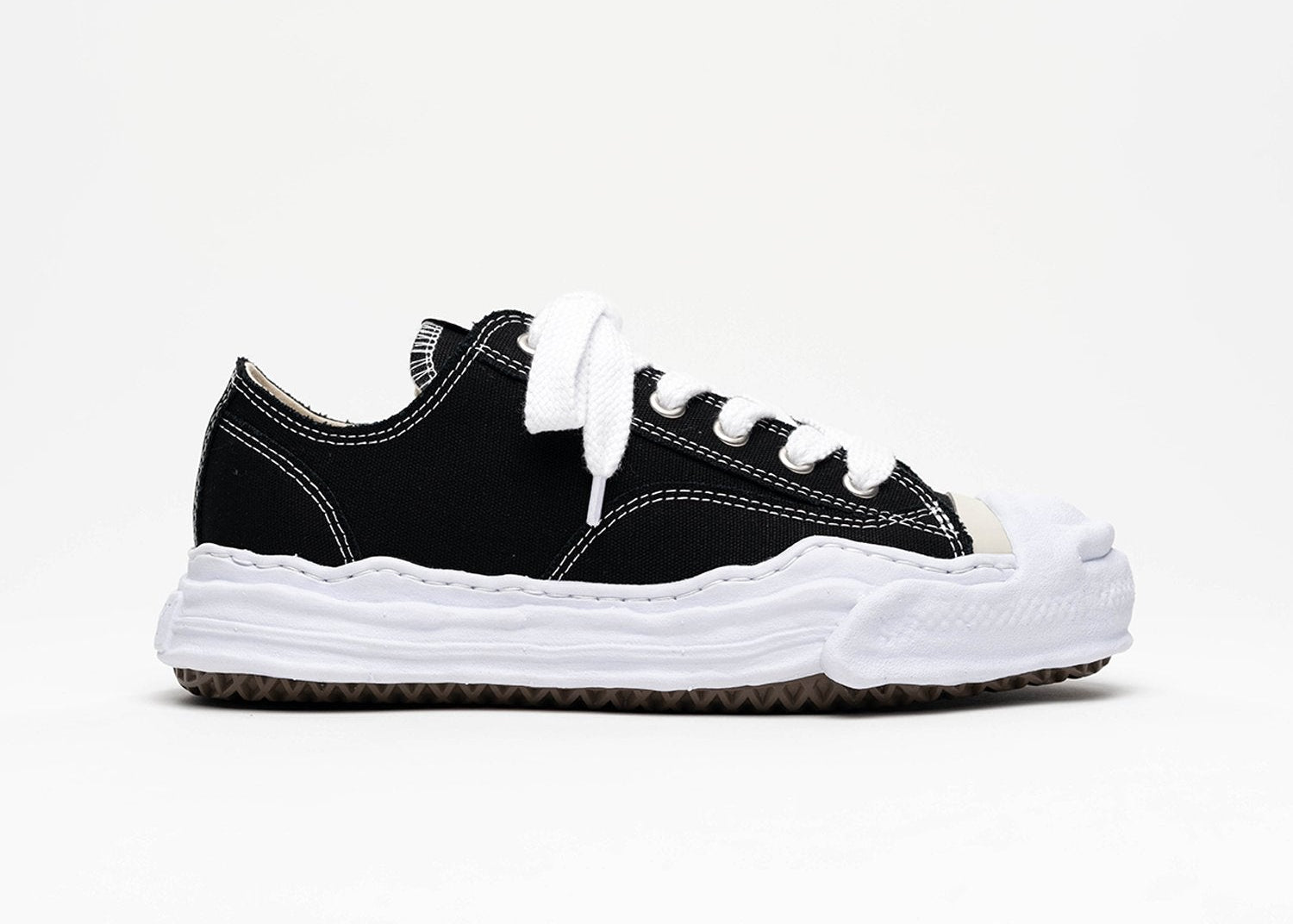 Découvrez la Maison Mihara Yasuhiro Hank OG Sole Canvas Low Black, une sneaker en toile noire avec semelle OG Sole sculptée en caoutchouc et silhouette basse au design expérimental.