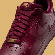 Sneakers Nike Air Force 1 Low Syna Central Cee Dark Beetroot en cuir bordeaux premium avec semelle Air et détails co-brandés exclusifs.
