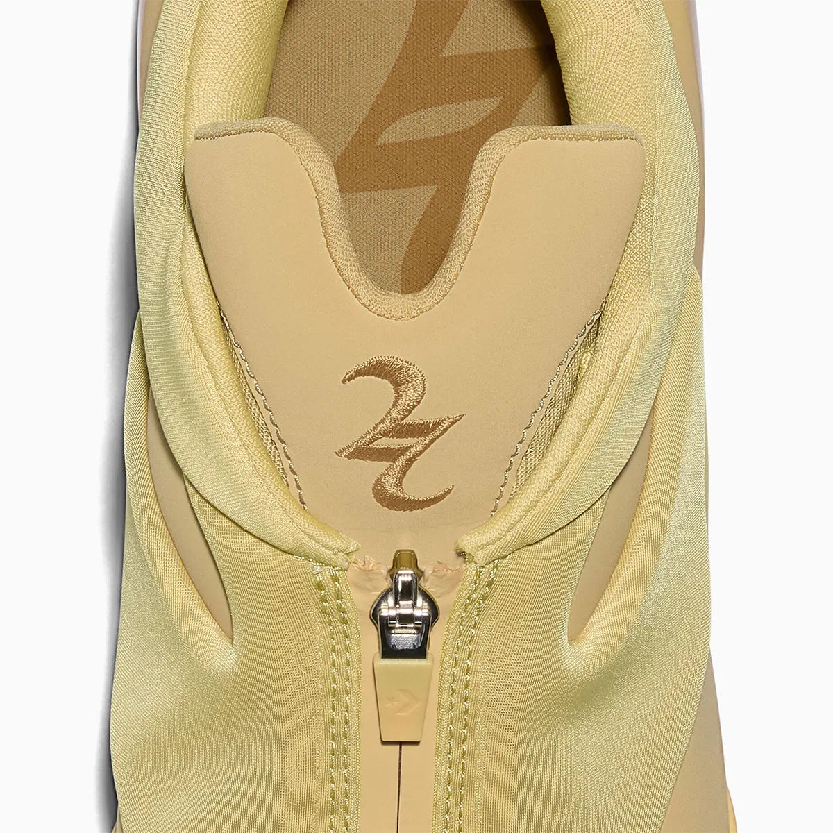 Converse SHAI 001 Butter, sneaker de basketball jaune crème monochrome avec empeigne moulée, fermeture zippée et silhouette futuriste.