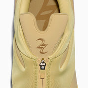 Converse SHAI 001 Butter, sneaker de basketball jaune crème monochrome avec empeigne moulée, fermeture zippée et silhouette futuriste.