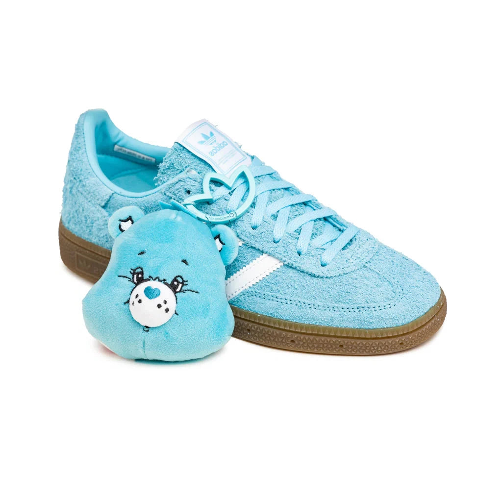 Adidas Handball Spezial Care Bears Bedtime Bear avec tige en daim premium, empiècements en cuir, détails Care Bears Bedtime Bear et semelle extérieure en gomme avec sa peluche vue de profil. 